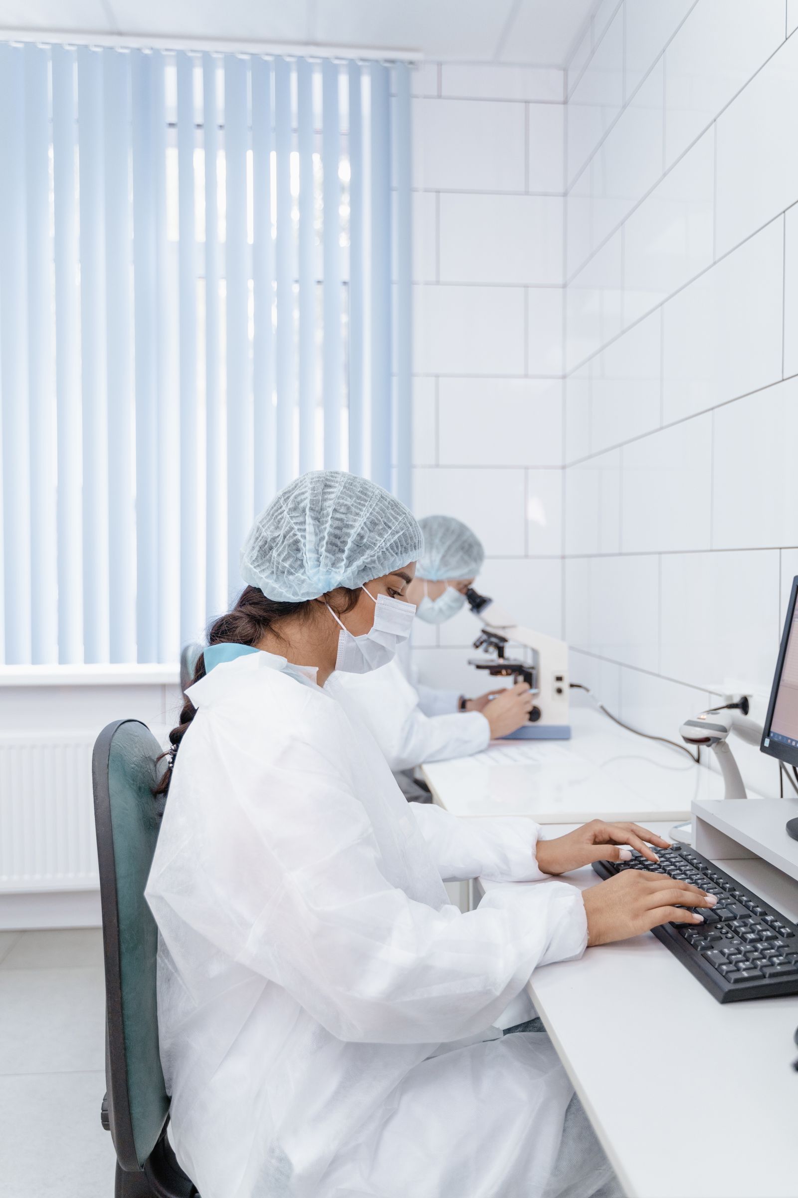 Laboratory staff working at computers in protective clothing.