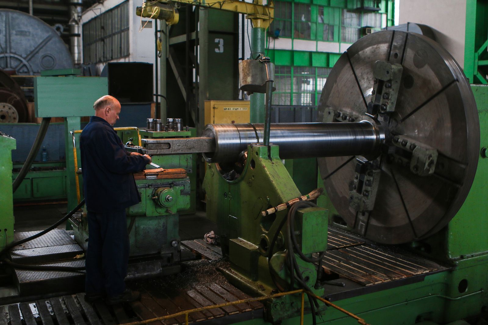 A worker beside large machinery on a manufacturing floor.