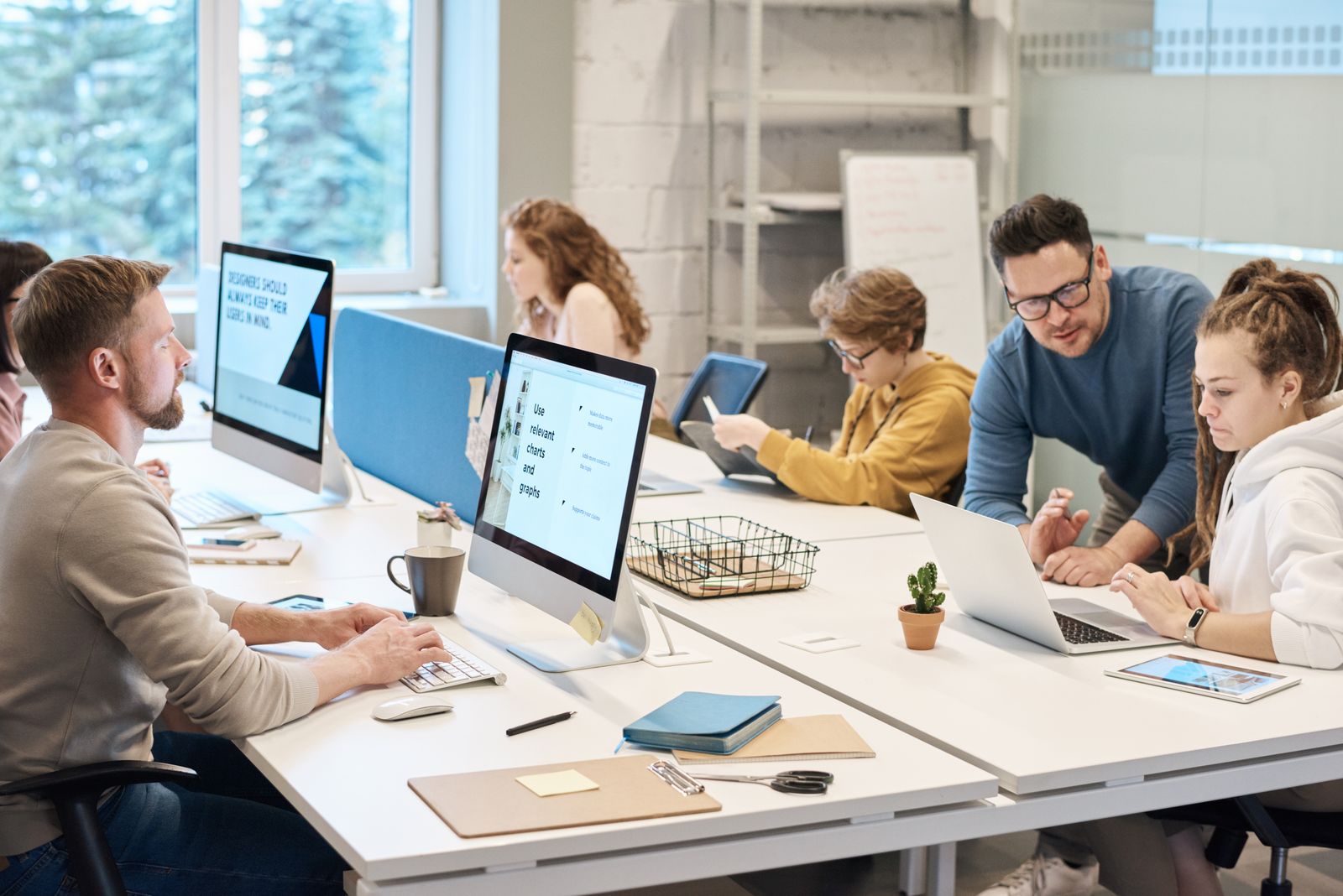 Colleagues discussing work at computers in a shared office.